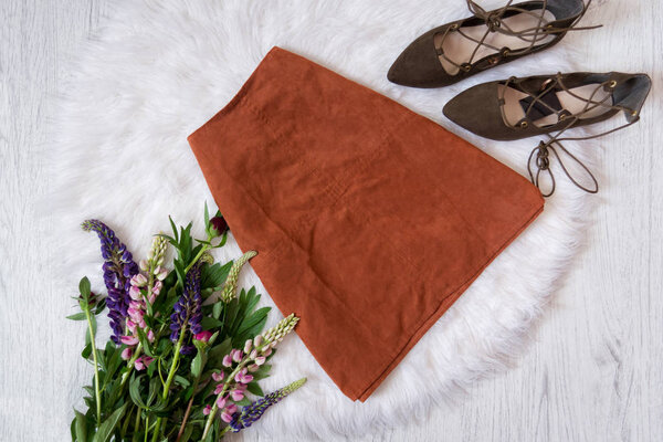 Brown suede skirt and shoes on white fur, a bouquet of flowers. Fashionable concept