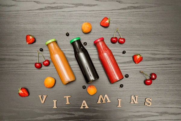 Üç şişe suyu, meyve ve yazıt vitaminler siyah ahşap zemin, gıda kavramı ile