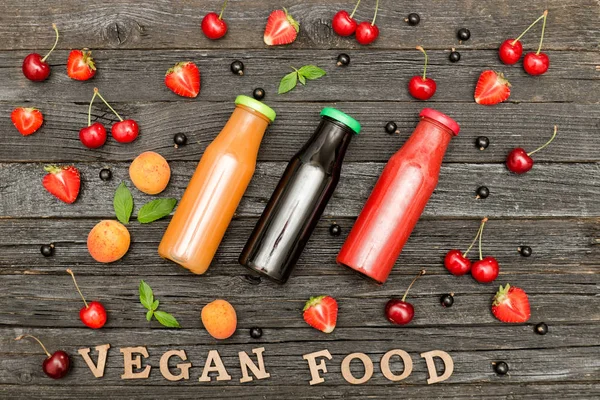 Üç şişe suyu, meyve ve ahşap arka plan, gıda kavramı üzerinde yazıt Vegan gıda