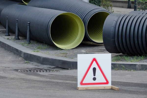 Sustitución de tuberías en la ciudad. Grandes tuberías nuevas. Señal de precaución —  Fotos de Stock