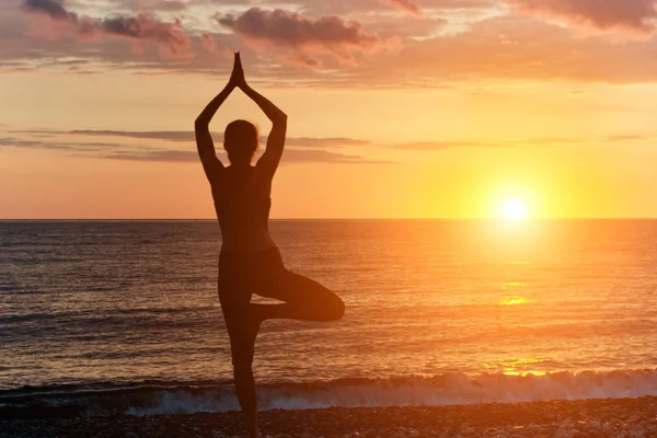 Flicka vid solnedgången praktisera yoga på stranden, siluett — Stockfoto