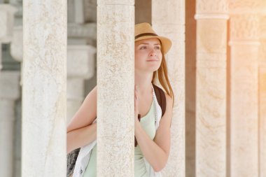 Şapkalı Kız Mermer sütunlar arasında duruyor. Yolculuk