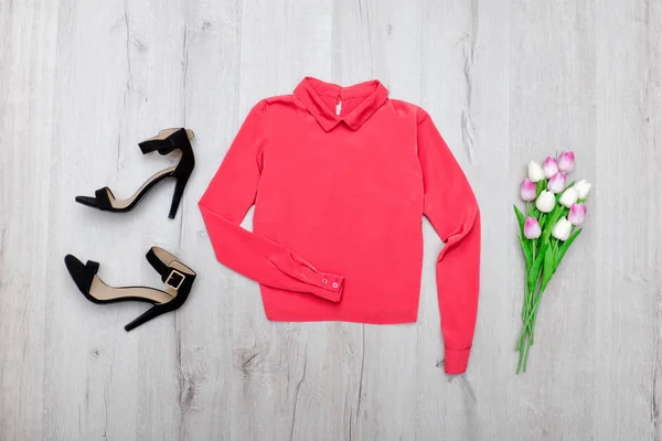Koraal bloes, zwarte schoenen, boeket tulpen. Modieuze concept. Houten achtergrond — Stockfoto