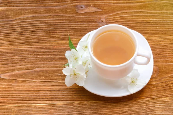 Beyaz bir fincan çay ile Yasemin ahşap bir masa üzerinde. Üstten Görünüm