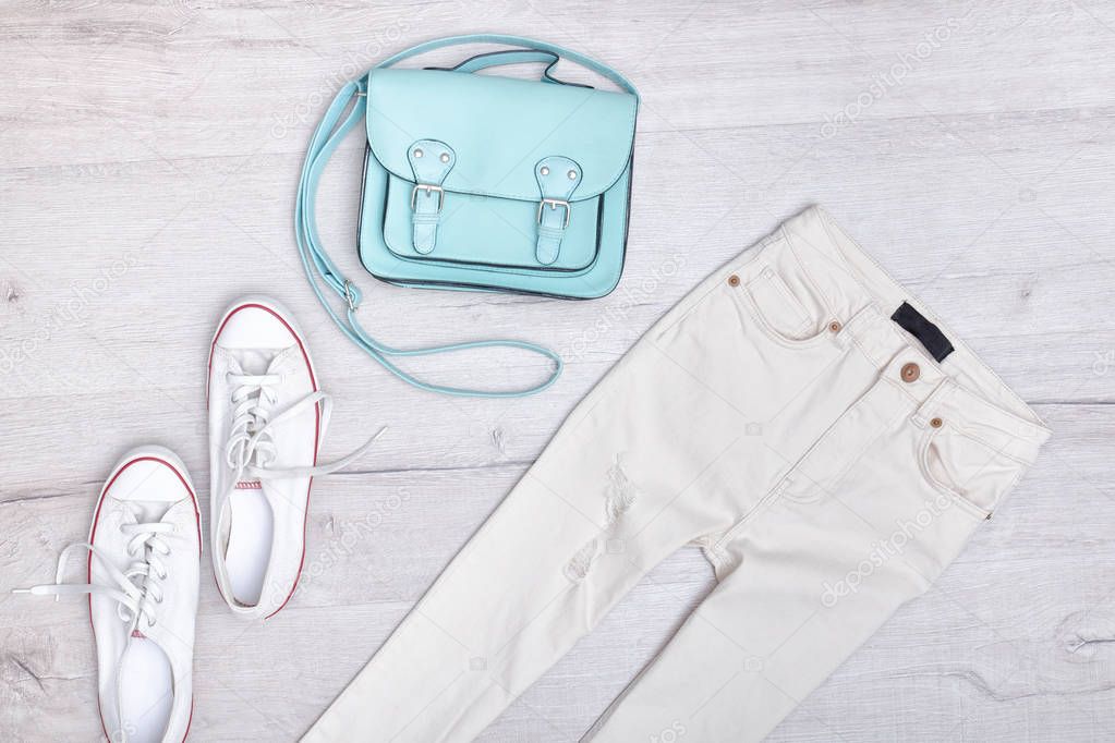 White jeans and sneakers, mint bag. Fashionable concept. Wooden background.