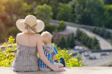 Anne ve oğlu yeşil orman ve köy uzakta arka plan üzerinde oturan