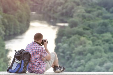Adam bir Hill orman ve nehir arka planda fotoğraf çeker