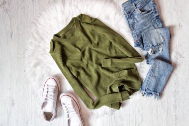 Haki kazak, kot pantolon ve beyaz spor ayakkabı sökük. Moda kavramı üzerinde beyaz kürk