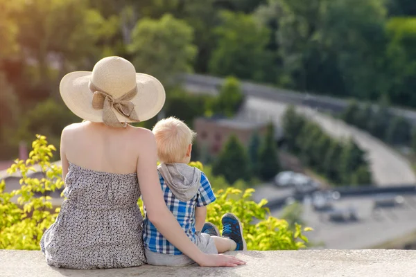 Anne ve oğlu yeşil orman ve köy uzakta arka plan üzerinde oturan