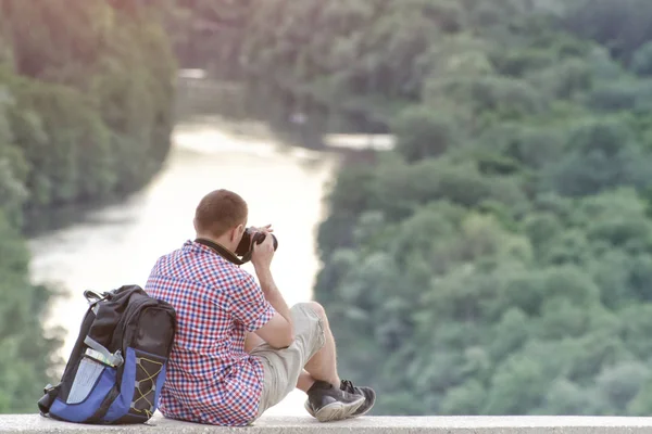 El hombre toma fotos de una colina en el fondo del bosque y el río — Foto de Stock