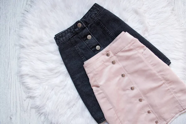 Чорно-рожеві джинсові спідниці з кнопками. Модна концепція, на білому фоні хутра — стокове фото
