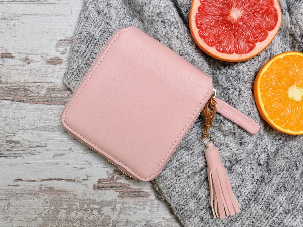 少しピンク レディース財布、セーターと木製の背景に柑橘類。ファッションの概念 — ストック写真