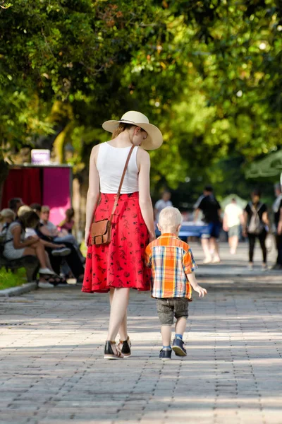 Anne ve oğlu parkta yürüyüş güneşli bir gün. Arkadan görüntülemek