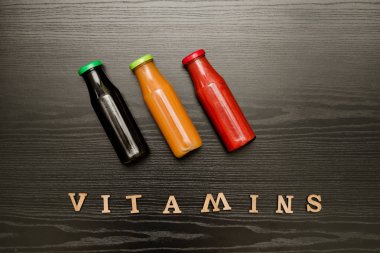 Üç şişe suyu ve yazıt vitaminler siyah ahşap zemin, gıda kavramı ile