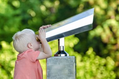 Küçük sarışın çocuk dürbün çifti büyük bir seyir. Park içinde belgili tanımlık geçmiş