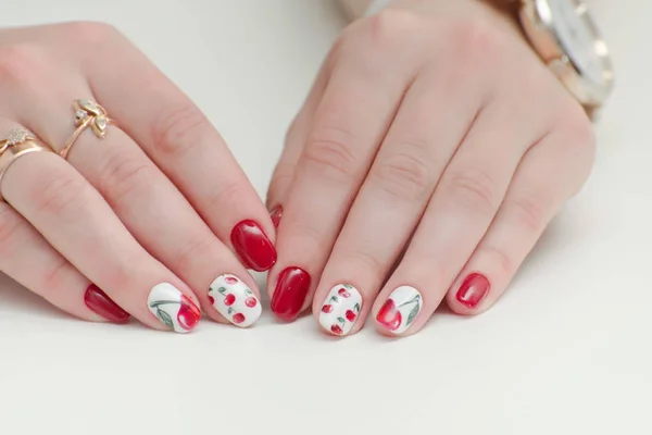Frauenhände mit Maniküre, rotem Nagellack, Zeichnung mit Kirschen. weißer Hintergrund. — Stockfoto