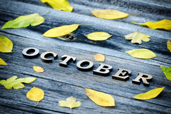 Ahşap arka plan üzerinde yazıt Ekim, çerçeve sarı yaprakları