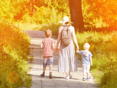 Anne ve oğlu yolun parkta yürüyorduk. Arkadan Görünüm. Güneşli gün
