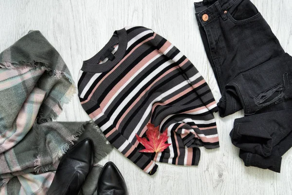 Sweter w paski, czarne dżinsy i szalik. Klon czerwony liść. Koncepcja modne — Zdjęcie stockowe