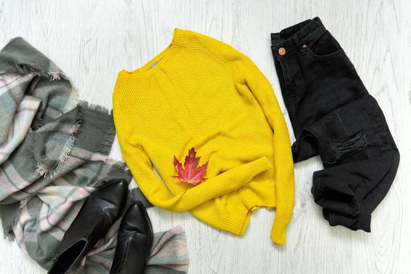 Κίτρινο πουλόβερ, μαύρο τζιν και κασκόλ. Κόκκινο φύλλο σφενδάμνου. Μοντέρνα έννοια — Φωτογραφία Αρχείου