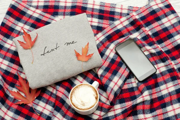 Yazıt, ekose, akıllı telefon, kapuçino kupa ve sonbahar yaprakları gri kazak. Moda kavramı