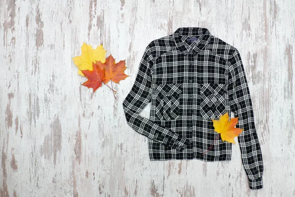 Black checkered shirt and maple leaves. Fashionable concept