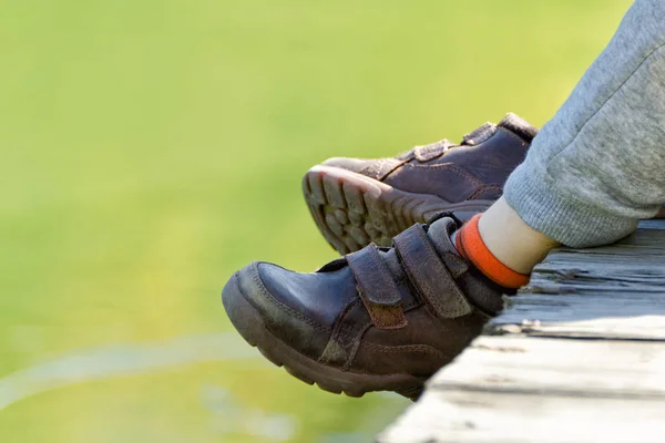 Los pies de los niños en zapatos de cuero marrón sobre el agua . — Foto de Stock