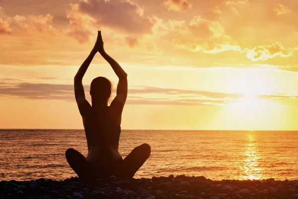 Meisje is het beoefenen van yoga op het strand. Uitzicht vanaf de achterkant, zonsondergang — Stockfoto