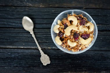 Granola kaju bir kapta, bir çay kaşığı ile. Siyah ahşap masa