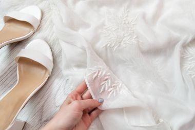 Bir el beyaz şeffaf kumaş. Beyaz ayakkabı. Moda kavramı