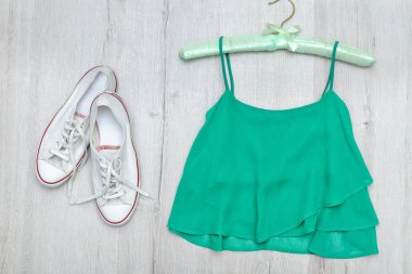 Yeşil üst ve beyaz spor ayakkabı. Moda kavramı. Ahşap arka plan