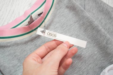 Kharkiv, Ukrayna - 11 Ağustos 2017: bir el Asos etiketinde beyaz. Gri elbise. Yakın çekim