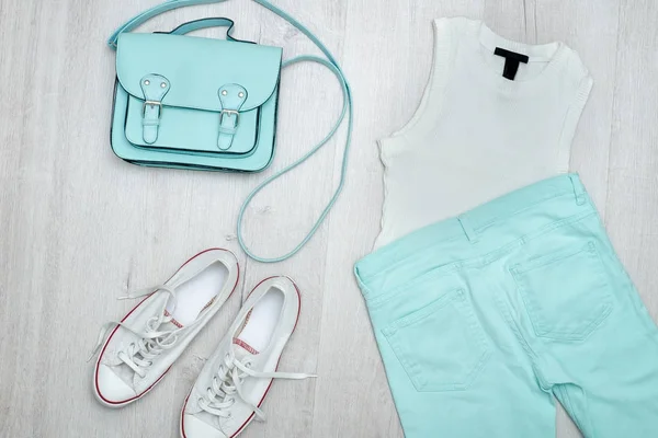Bílý top, máta barevné džíny, bílé tenisky a kabelku. Módní pojem. Dřevěné pozadí. — Stock fotografie