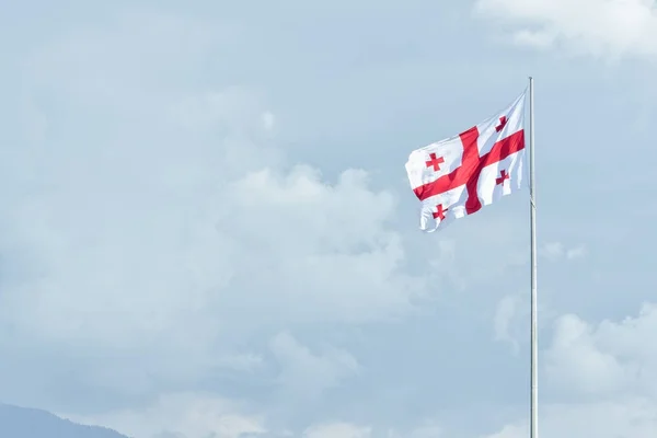 Bandeira da Geórgia na bandeira. Céu e nuvens no fundo — Fotografia de Stock