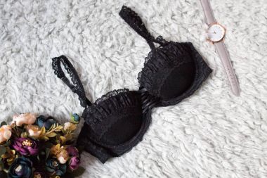 Siyah dantel büstiyer kürk üzerinde. Kol saati ve bir buket çiçek