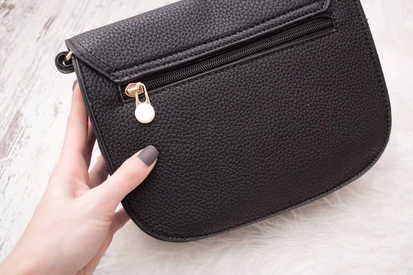 Black small bag in a female hand. Fashionable concept.