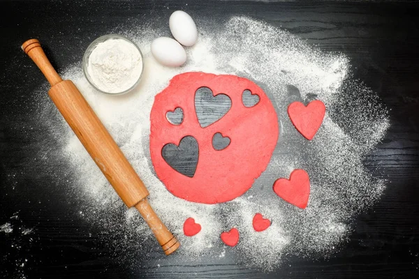 Oklava, yumurta ve un ile hamur kırmızı kalpler kesip — Stok fotoğraf