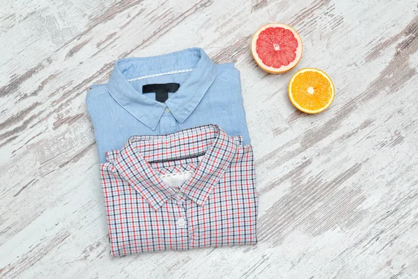 Blue an checkered shirt on a wooden background, halves of citrus
