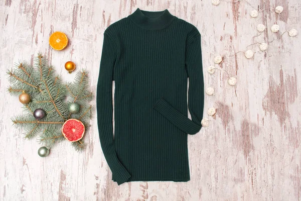 Green sweater, a decorated fir branch and a garland — Stock Photo, Image