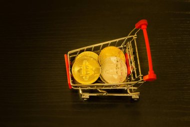 Alışveriş sepeti içinde Bitcoin paralar. Siyah arka plan