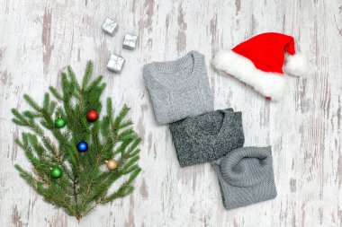 Üç gri süveterli, Noel Baba'nın şapka ve köknar dalı ahşap arka plan üzerinde