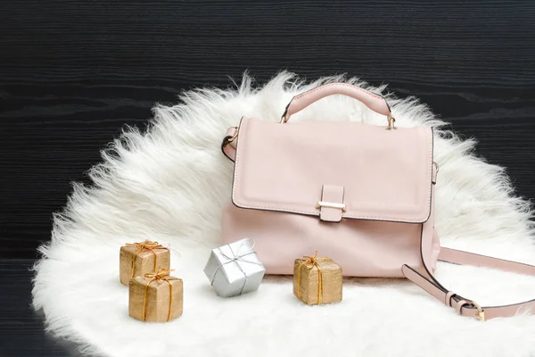 Pink bag and gift box on white fur, black table — Stock Photo, Image