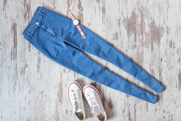 Calça jeans azul e tênis branco em fundo de madeira — Fotografia de Stock