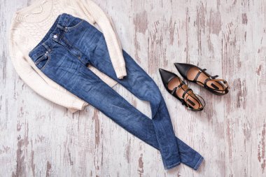 Mavi kot pantolon, kazak ve ahşap arka plan üzerinde siyah ayakkabılar. Moda kolaj