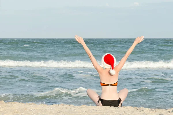 Noel Baba şapkaları kız. Deniz kıyısında. Eller yukarı kaldırdı. — Stok fotoğraf