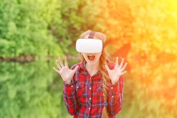 Girl in a helmet of virtual reality on a background of nature