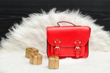 Kırmızı çanta ve mini hediye kutusu beyaz kürk üzerinde. Moda kavramı.