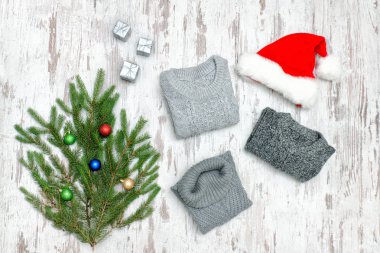 Üç gri süveterli, Noel Baba'nın şapka ve köknar dalı ahşap arka plan üzerinde