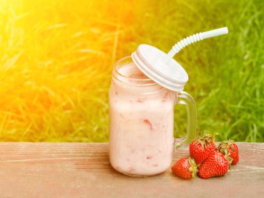 Yoğurt ve çilek yeşil çim bir arka plan üzerine bir fincan