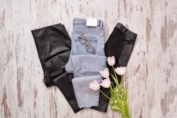 Pantalones vaqueros azules y leggins de cuero negro, gafas, tulipanes rosados — Foto de Stock